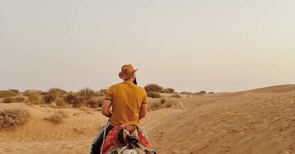 A person rides a camel through India's Thar Desert during a beautiful sunset.